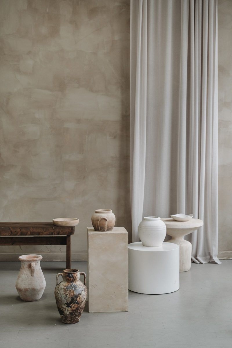 Stoneware vessels standing on plinths in a pale room